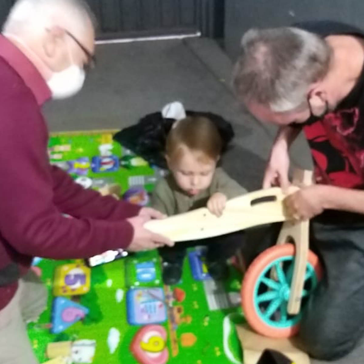 Humberto, o filho Antônio e o avô montando a Biciquetinha no chão da garagem