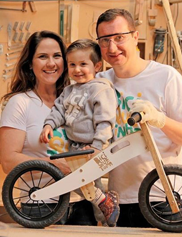 Gilson e Maria Fernanda com o filho Gabriel no início da Biciquetinha, em 2017, na oficina com uma das primeiras bicicletas de madeira