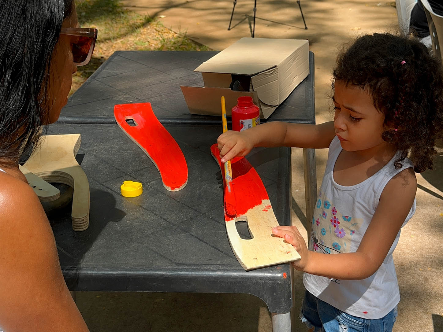 Criança pintando a peça da Biciquetinha de vermelho